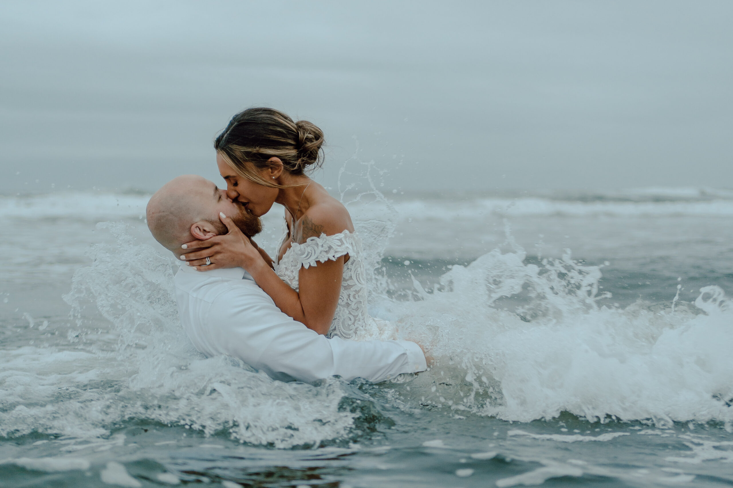 Bride and groom kissing in the ocean in Westport, Washington